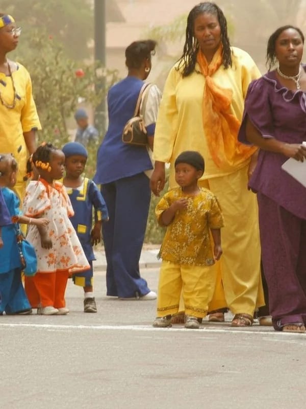 Families walking together in colourful traditional outfits in the Village of Peace